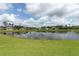 Scenic water view homes showcase a serene lake surrounded by lush green lawn under a blue sky with fluffy clouds at 1313 Middle Lake Dr, Ormond Beach, FL 32174