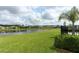 Picturesque water view homes featuring a tranquil lake and meticulously maintained green lawn with palm tree under a cloudy sky at 1313 Middle Lake Dr, Ormond Beach, FL 32174