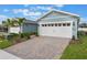 Light blue home exterior featuring a two-car garage with brick paver driveway and mature landscaping at 13562 Pearl Beach St, Winter Garden, FL 34787