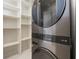 Laundry room with stacked washer and dryer and custom shelving for storage at 13562 Pearl Beach St, Winter Garden, FL 34787