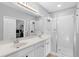 Bathroom with double sinks, white cabinets, large mirror, and glass-enclosed shower at 14126 Walcott Ave, Orlando, FL 32827
