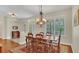 Dining room with hardwood floors, chandelier, shuttered window and a dark wood table with six chairs, plus an archway to another room at 14312 Paradise Tree Dr, Orlando, FL 32828