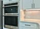 Modern kitchen with built-in stainless steel ovens and white cabinetry at 148 Hampton Loop, Davenport, FL 33837