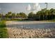 Sandy volleyball court bordered by lush landscaping and palm trees on a sunny day at 1836 Sandy Park Trl, Kissimmee, FL 34747