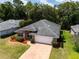 Aerial view of brick home showcasing landscaped yard, new roof, and brick driveway, nestled in a lush, green neighborhood at 2085 Friar Tuck Ln, Orange City, FL 32763