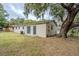 View of the backyard showing the exterior of the home and a large shade tree at 2311 Olivet Ave, Leesburg, FL 34748