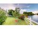Scenic backyard featuring lush landscaping, a white fence, and a tranquil lake view at 2506 Shelby Cir, Kissimmee, FL 34743
