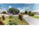 Well-manicured front yard featuring mature trees, lush lawn, and colorful landscaping at 2506 Shelby Cir, Kissimmee, FL 34743