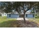 View of blue home exterior showing backyard, patio, sliding door, and tree at 2963 Beckwith St, Deltona, FL 32738
