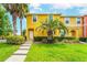 Inviting townhome features sunny yellow exterior, lush lawn, and well-maintained landscaping with palm trees at 3002 Secret Lake Dr, Kissimmee, FL 34747