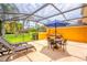 Relaxing screened patio features lounge chairs, seating area with umbrella table and a private hot tub at 3002 Secret Lake Dr, Kissimmee, FL 34747