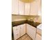Compact kitchen featuring white cabinets, dark countertops, a farmhouse sink, and tiled floors at 319 N Scenic Hwy, Frostproof, FL 33843