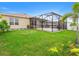 Landscaped backyard featuring a covered lanai, white picket fence, and lush green grass at 341 Alexzander Way, Winter Haven, FL 33881