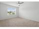 Bright bedroom features a ceiling fan, neutral carpet, and a large window overlooking the yard at 341 Alexzander Way, Winter Haven, FL 33881