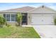 Close up of charming single-story home featuring a neutral paint scheme and a two-car garage with a well manicured lawn at 341 Alexzander Way, Winter Haven, FL 33881