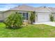 Well-maintained lawn and landscape adorn this single-story home with a two car garage in this exterior home view at 341 Alexzander Way, Winter Haven, FL 33881