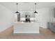 Open kitchen features a modern island with sink, pendant lights, and stainless appliances at 341 Alexzander Way, Winter Haven, FL 33881