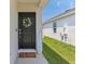 Inviting front entrance with a stylish black door, floral wreath, 'Welcome' sign, and 'hello spring' doormat at 4122 Sagefield Dr, St Cloud, FL 34773