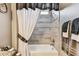 Well-lit tub/shower combo featuring neutral toned tile and a white shower curtain at 4133 Foxhound Dr, Clermont, FL 34711