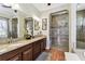 Bathroom featuring double sinks, dark wood cabinets, granite counters, and a tiled shower with mosaic accents at 4133 Foxhound Dr, Clermont, FL 34711