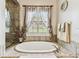 Freestanding bathtub by window with decorative curtains at 4133 Foxhound Dr, Clermont, FL 34711