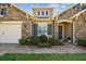 Charming home showcasing stone accents, blue shutters, and a well-manicured lawn with flower beds at 4133 Foxhound Dr, Clermont, FL 34711