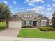 Beautiful single-Gathering home with a stone facade, paver driveway, manicured lawn, and blue shutters at 4133 Foxhound Dr, Clermont, FL 34711