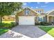 Charming stone home featuring a two-car garage with brick paver driveway and lush landscaping at 4133 Foxhound Dr, Clermont, FL 34711