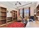 Bright home office with built-in wooden bookshelves, tray ceiling, and a large window overlooking the landscaped yard at 4133 Foxhound Dr, Clermont, FL 34711