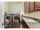 Functional laundry room with stainless steel washer and dryer, ample counter space, and storage cabinets at 4133 Foxhound Dr, Clermont, FL 34711