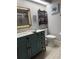 Bathroom features a blue vanity, framed mirror, toilet and decorative shelving with wall art at 4186 Buglers Rest Pl, Casselberry, FL 32707