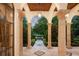 A stunning arched entryway featuring a tiled walkway, lush landscaping, and view of the mature trees at 4400 New Broad St, Orlando, FL 32814