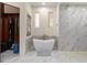Bathroom featuring a soaking tub with marble surround, built-in shelves, and closet access at 4400 New Broad St, Orlando, FL 32814