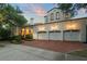 Elegant home with a three-car garage, brick driveway, lush landscaping, and Mediterranean-style architecture at 4400 New Broad St, Orlando, FL 32814