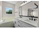Bathroom with a double sink vanity, granite countertop, black hardware, mirror, and a soaking tub at 461 Black Knight Way, Longwood, FL 32779