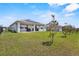Spacious backyard featuring a covered patio, lush green lawn, and tidy landscaping with solar panels on the roof at 5220 Red Coral Cir, Mount Dora, FL 32757
