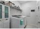 Bright laundry room with modern washer and dryer, storage cabinets, and shelving, perfect for household tasks at 5220 Red Coral Cir, Mount Dora, FL 32757