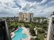 Scenic aerial view featuring a pool, manicured lawns, palm trees, and a beautiful building at 6165 Carrier Dr # 1801, Orlando, FL 32819