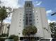 Modern condominium building featuring an elegant entrance and large windows, surrounded by lush landscaping at 6165 Carrier Dr # 1801, Orlando, FL 32819
