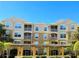 A tan and light brown apartment building featuring multiple screened balconies and well manicured landscaping on a sunny day at 6451 Old Park Ln # 407, Orlando, FL 32835