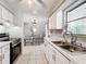 Kitchen featuring stainless steel sink, white cabinets, and view into the adjacent dining area with table and chairs at 7375 Lake Dr, Sanford, FL 32771