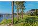 A scenic view of a lakefront backyard featuring lush greenery, tall trees, and a private dock with a covered seating area at 7550 John Hancock Dr, Winter Garden, FL 34787