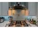 Close-up of a modern gas stovetop and stainless steel hood with custom tile backsplash at 7550 John Hancock Dr, Winter Garden, FL 34787