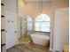 Bright bathroom featuring a luxurious tub beneath an arched window and a glass door shower at 787 High Grove Park Ct, Oviedo, FL 32765