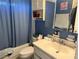 Bathroom with blue walls, white vanity, and combination shower and tub at 11314 Huggins St, Leesburg, FL 34788