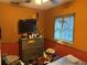 Bedroom with textured orange walls, window and a vintage dresser at 11314 Huggins St, Leesburg, FL 34788