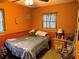 Bedroom with textured orange walls, two windows, and a vintage nightstand at 11314 Huggins St, Leesburg, FL 34788