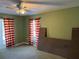 Bedroom with a ceiling fan, two windows, and red and cream striped curtains at 11314 Huggins St, Leesburg, FL 34788