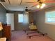 Bedroom with wood-paneled walls, carpeted floor, two ceiling fans and two windows at 11314 Huggins St, Leesburg, FL 34788