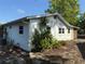 The back exterior of the home showcases landscaping with tropical plants and white-painted cinderblock at 11314 Huggins St, Leesburg, FL 34788